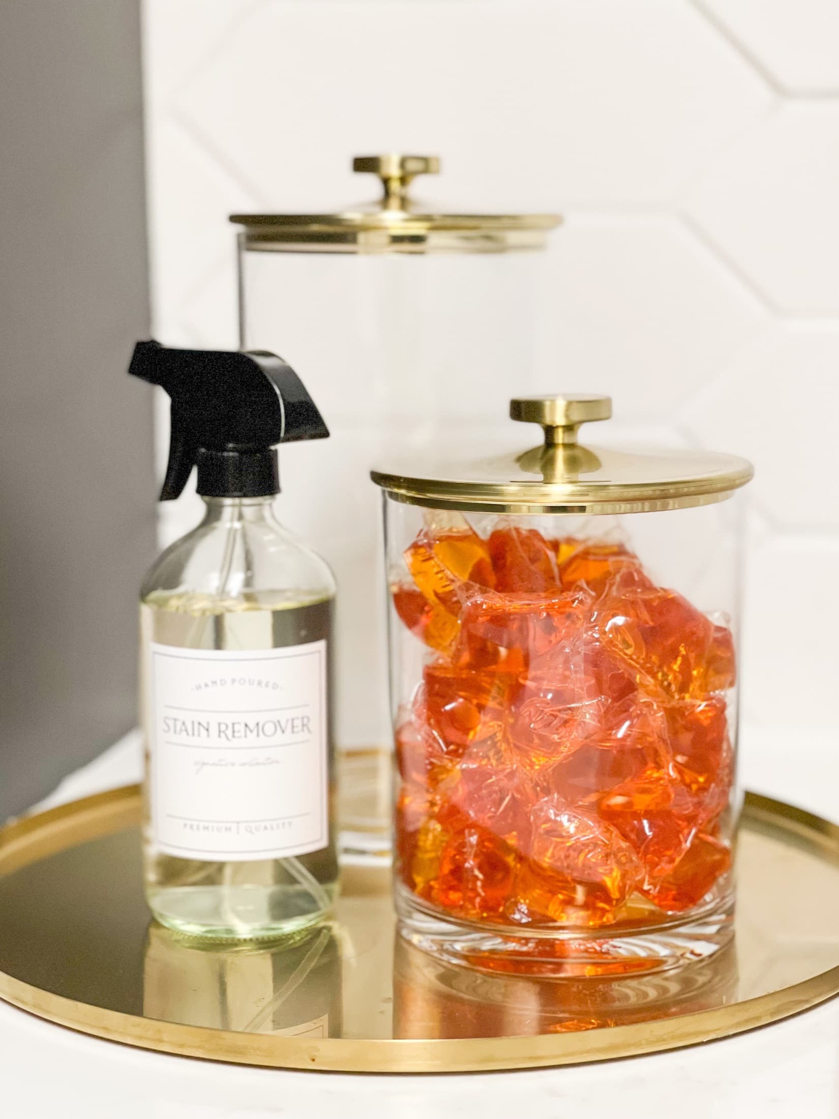 Brass-lidded glass jars styled on a gold tray in a laundry room