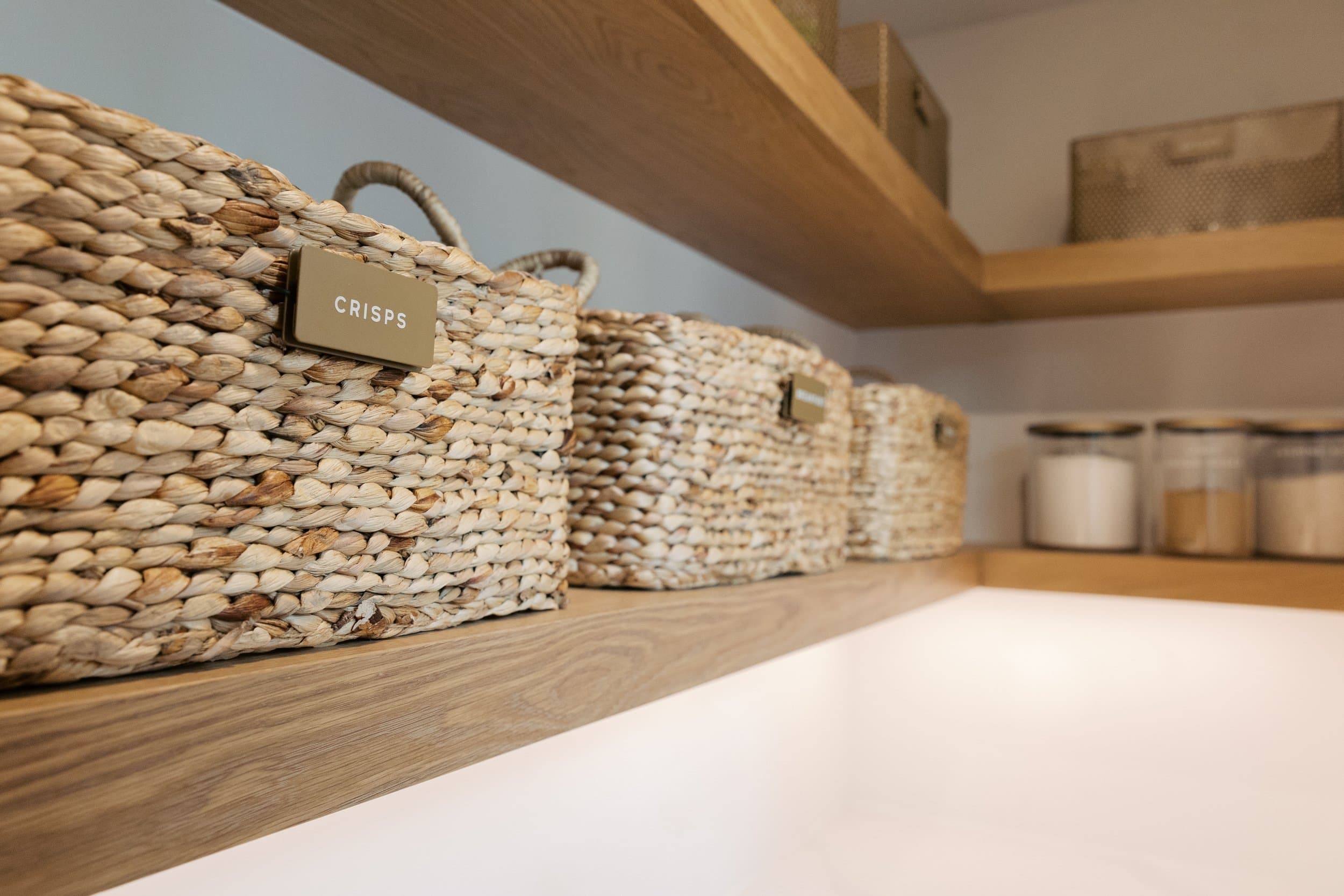 Labeled woven baskets on oak pantry shelving