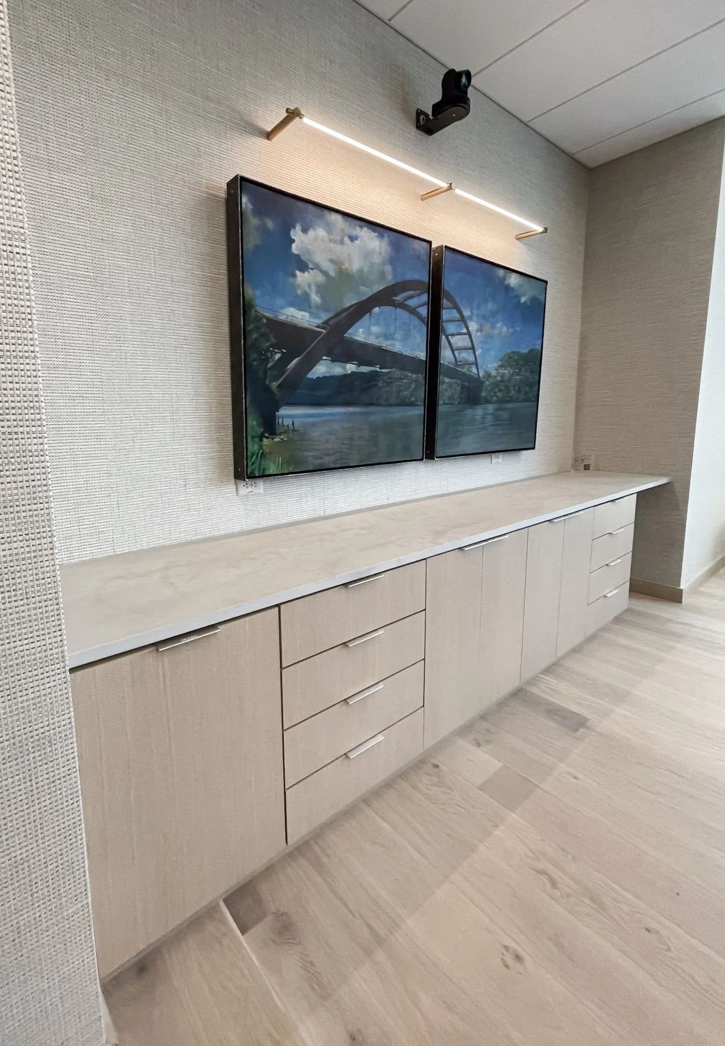 Office wall of light oak cabinetry beneath a framed Austin skyline print