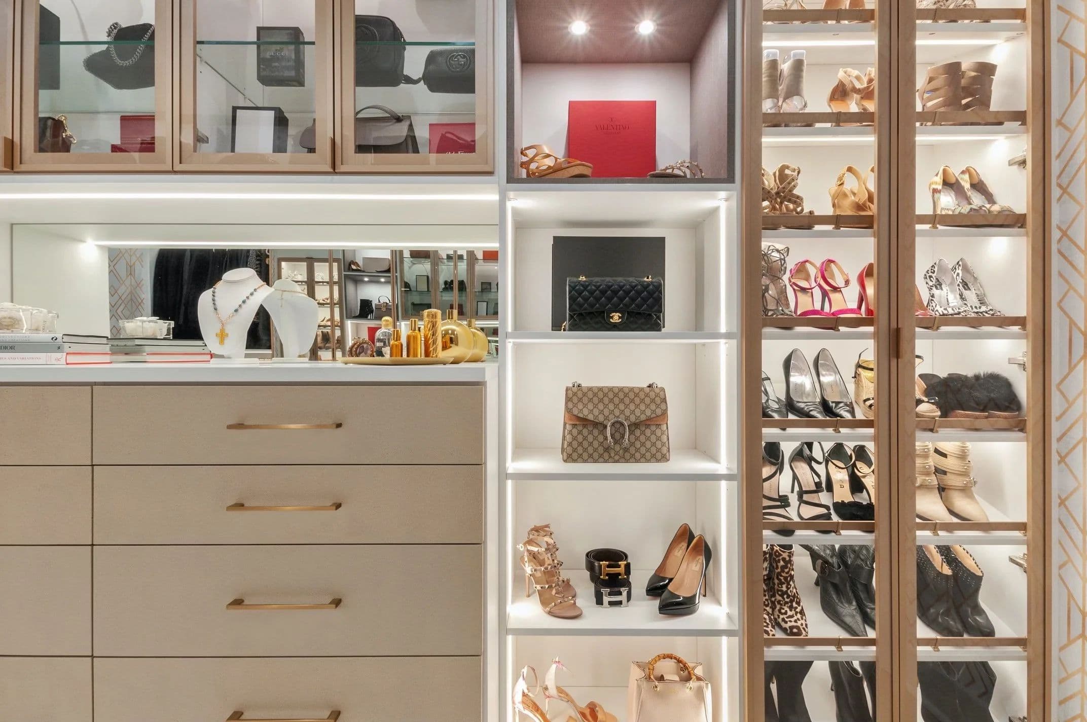 Custom closet with a lit vanity, glass-front cabinets and built-in drawers