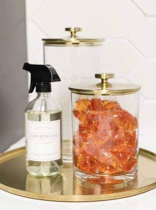 Glass cleaning bottle and brass-lidded jar on a gold tray