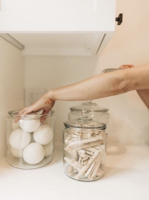 Reaching for wool dryer balls in glass storage jars