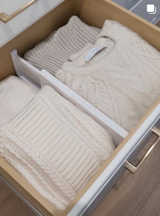Cream knit sweaters filed in a drawer with dividers