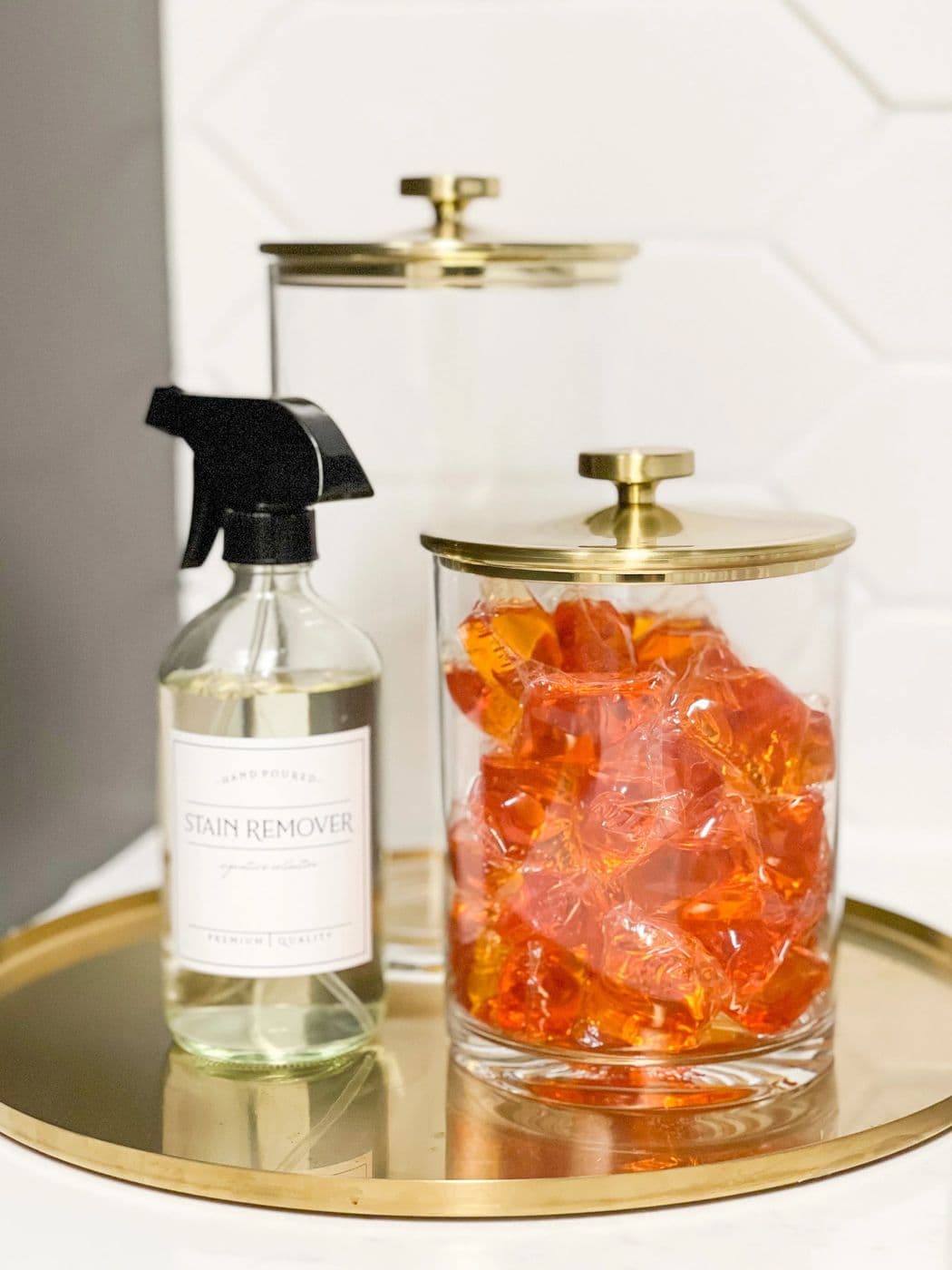 Glass cleaning bottle and brass-lidded jar on a gold tray