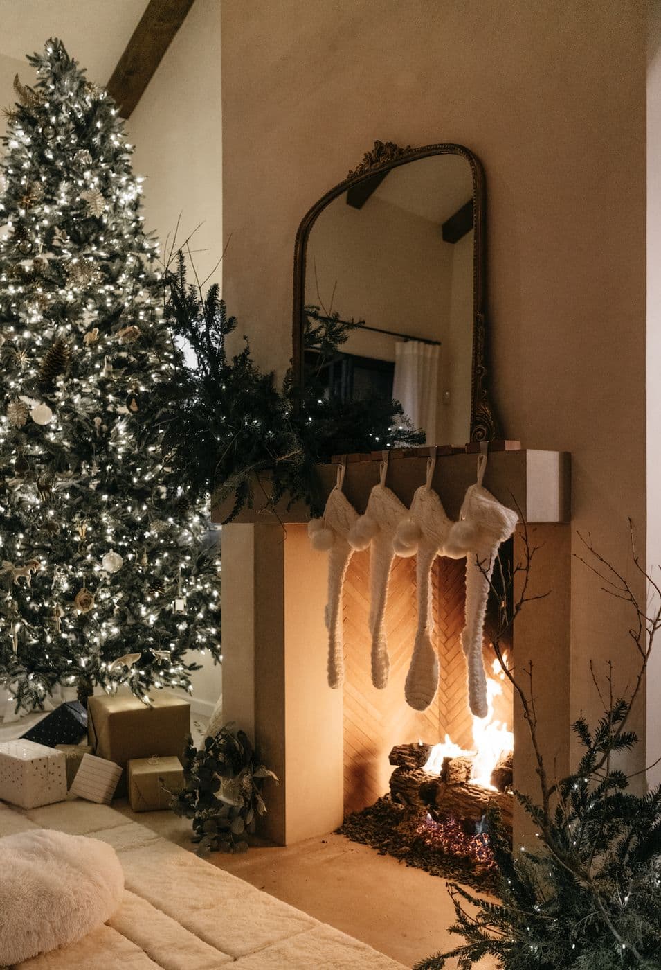 Lit fireplace with knit stockings, garland and a glowing Christmas tree