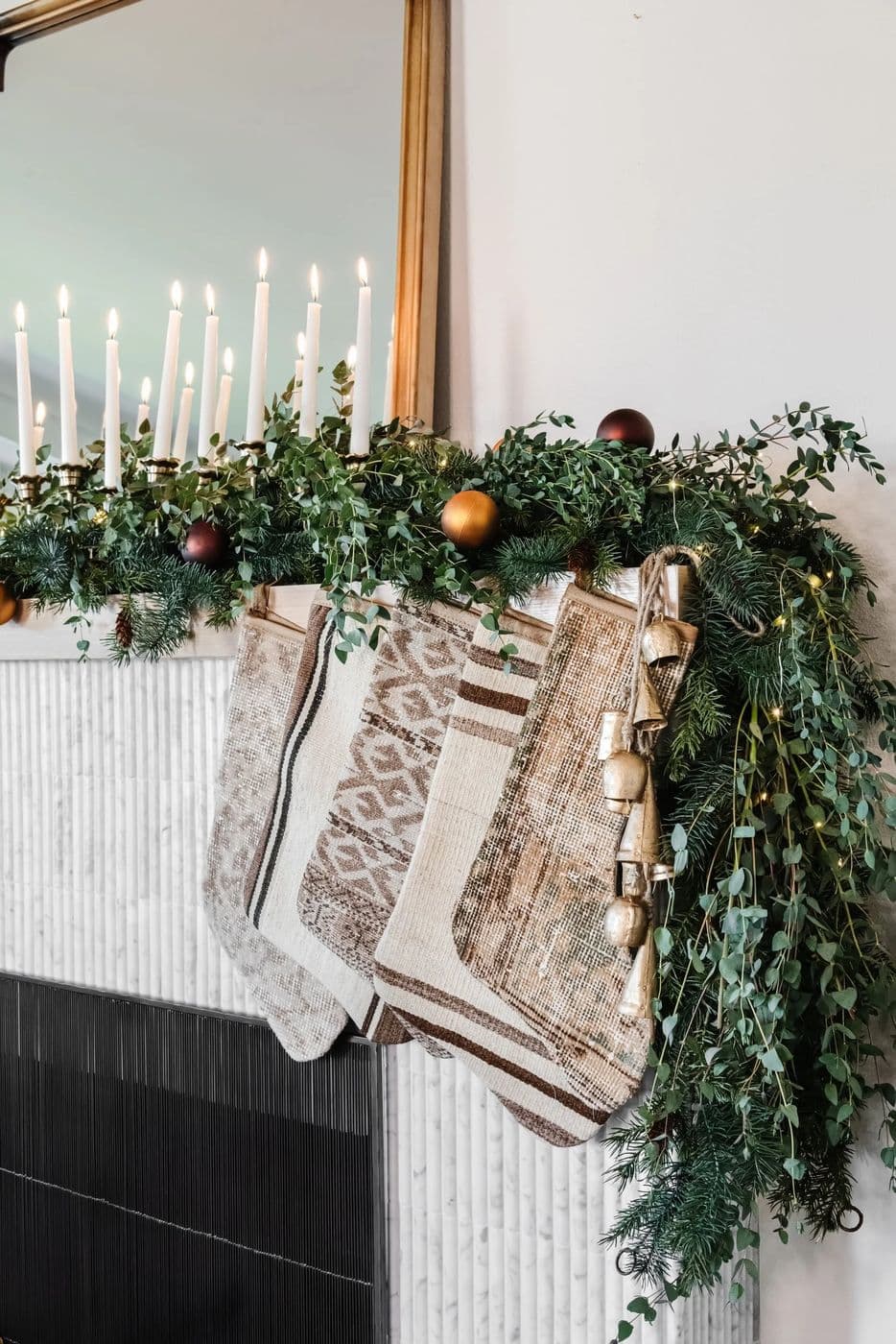 Holiday mantel with taper candles, garland and woven stockings