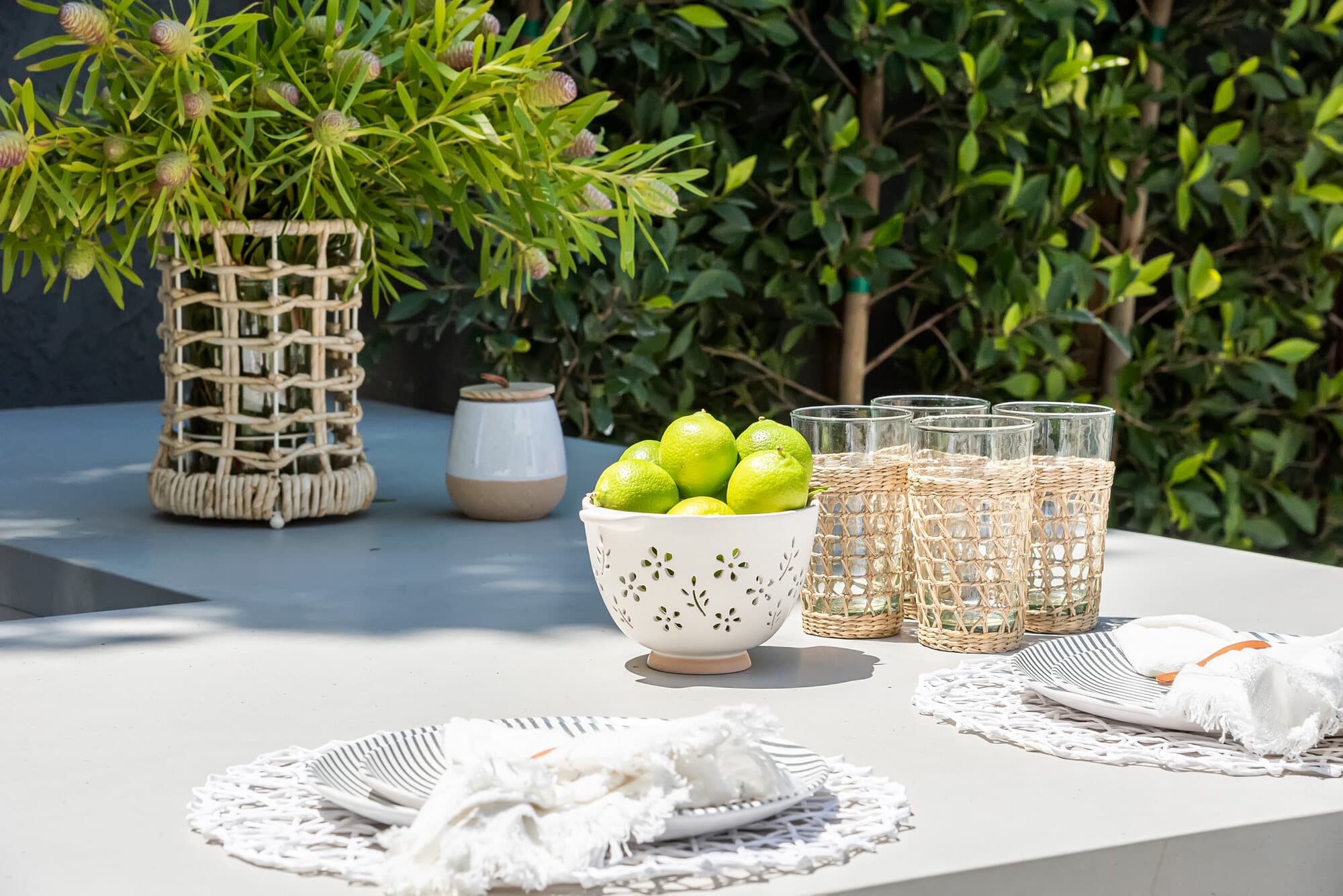 Styled outdoor table with woven vases, fresh lemons, and textured glassware