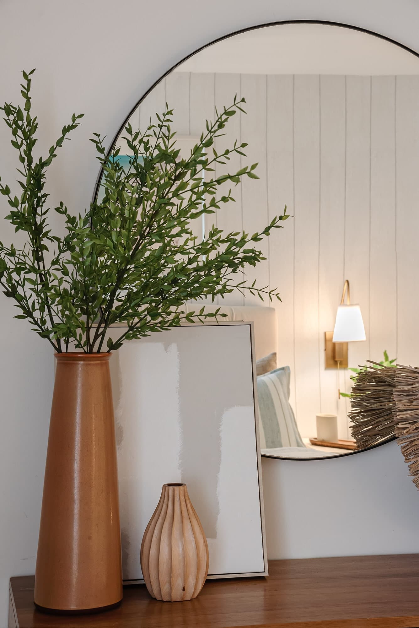 Entry console styled with an arched mirror, a terracotta vase, and olive branches